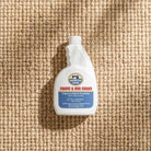 Fabric and rug guard spray bottle on a textured beige surface
