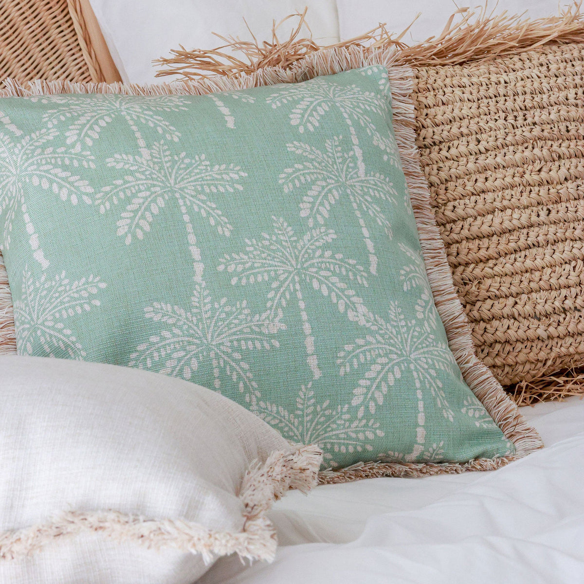 Green pillow with palm tree pattern on a textured surface