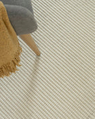 white rug with chair sitting on top and yellow throw