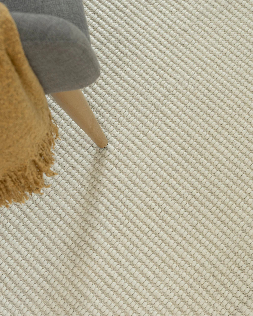 white rug with chair sitting on top and yellow throw