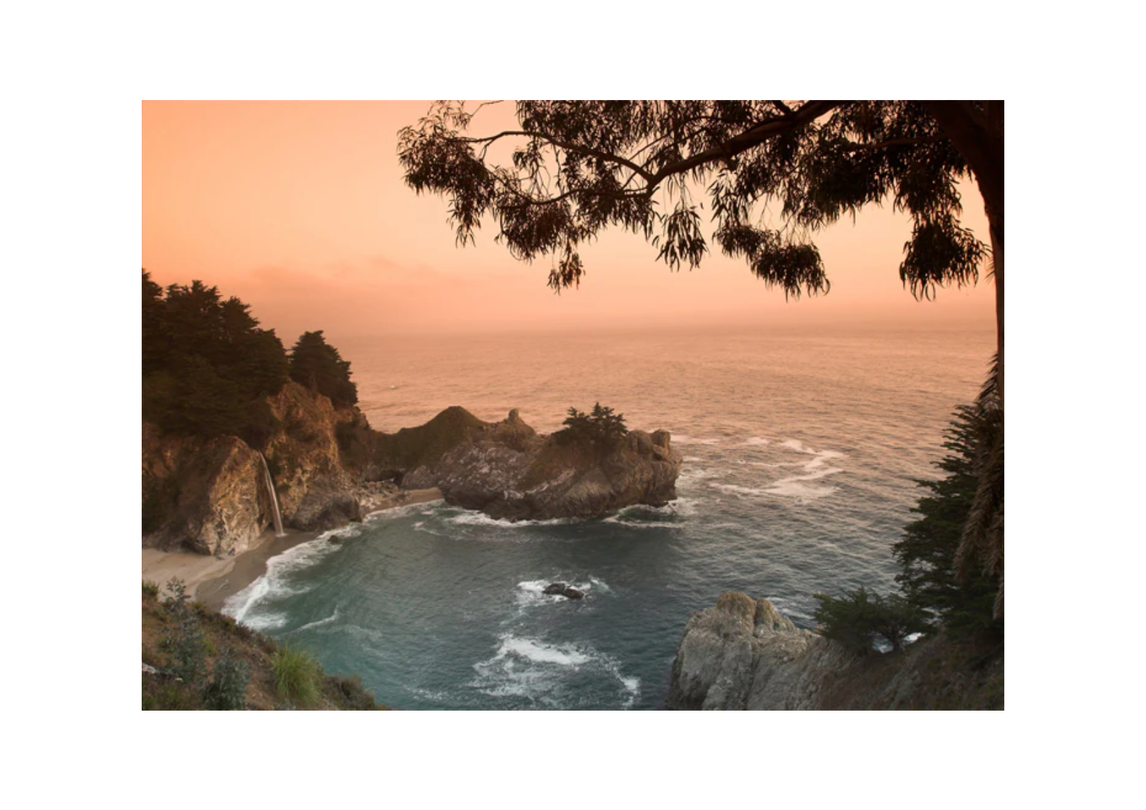 A scenic landscape photograph of a rocky coastal inlet at sunset, with orange sky, blue-green ocean water, dark cliffs, and tree silhouettes framing the top and right edges, shown on a white background.