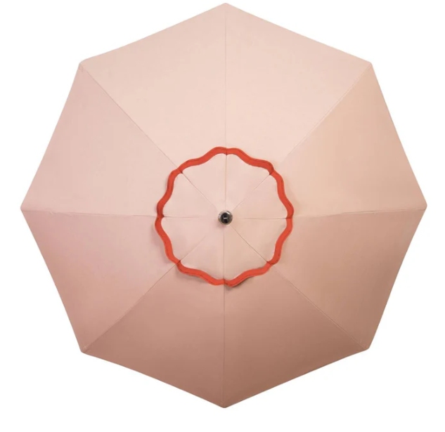 Beige patio umbrella with red trim on a white background