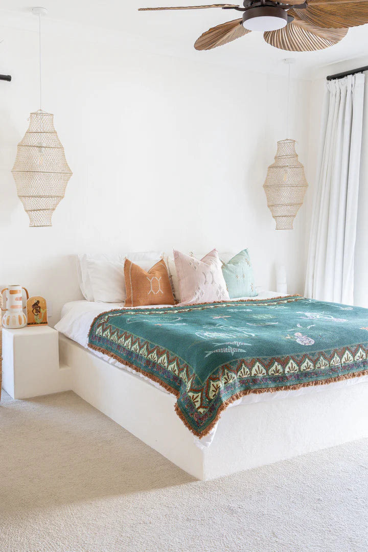 Bedroom with a bed featuring a green patterned blanket and colorful pillows.