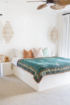 Bedroom with a bed featuring a green patterned blanket and colorful pillows.
