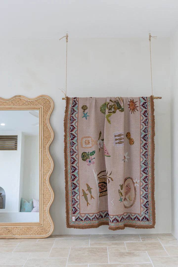 Decorative tapestry with intricate patterns hanging on a wall next to a mirror.