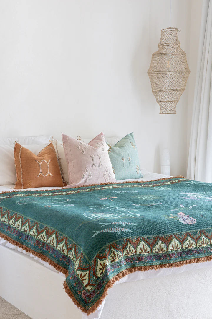 Bed with decorative pillows and a patterned blanket in a bedroom setting.