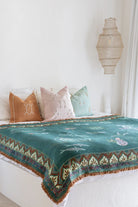 Bed with decorative pillows and a patterned blanket in a bedroom setting.