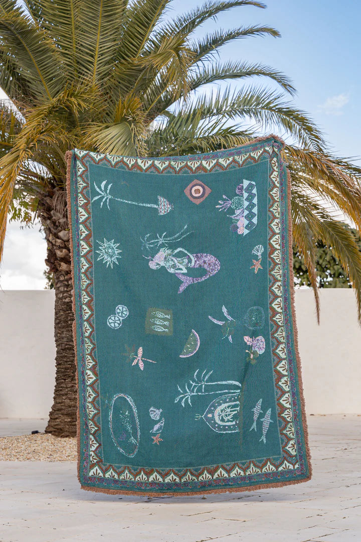 Decorative towel with mermaid design hanging on a palm tree
