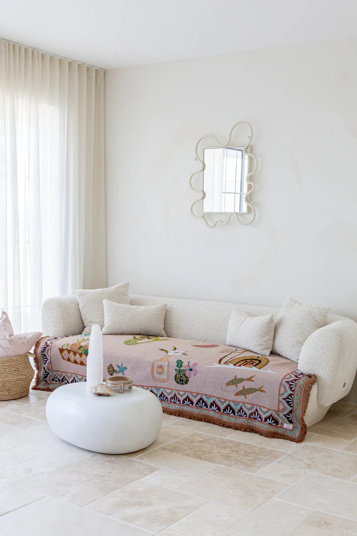 Living room with a white sofa, decorative pillow, and mirror on a white wall.