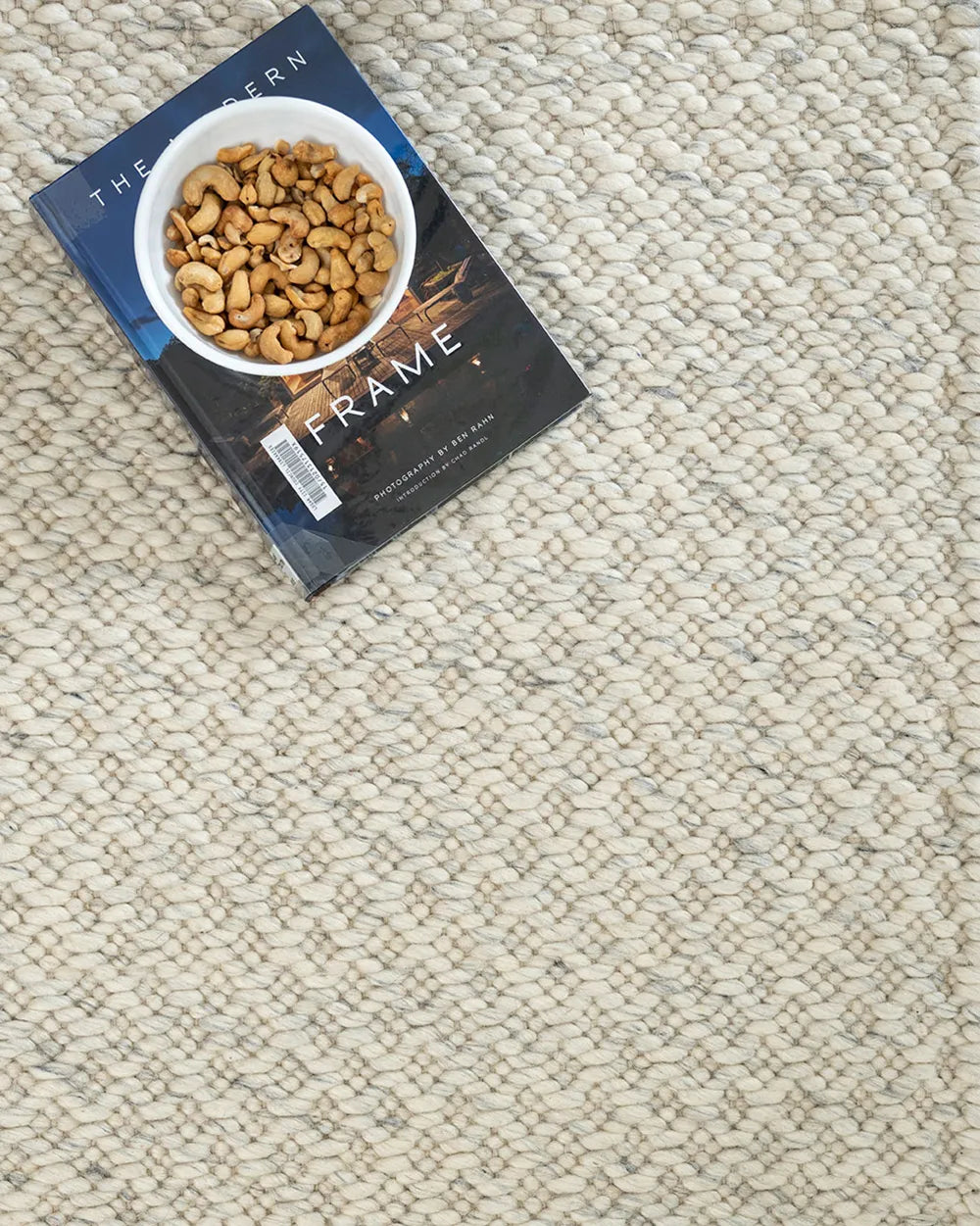 Book titled 'The Frame' on a textured rug