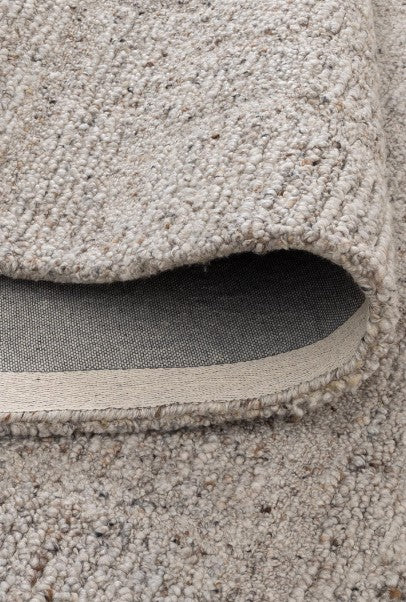 Close-up of a textured beige carpet with a visible edge.