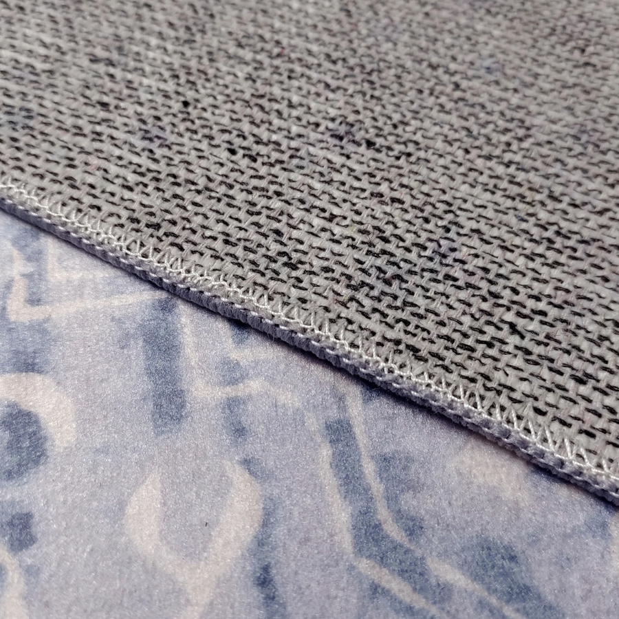Close-up of gray fabric with a textured pattern and visible stitching.