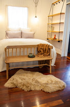 Bedroom with wooden bench, rug, and shelves.