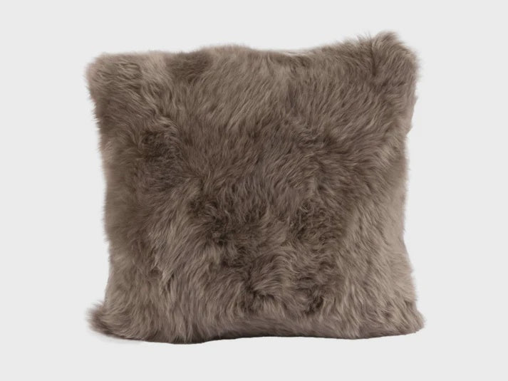 Fluffy brown sheepskin pillow on a white background