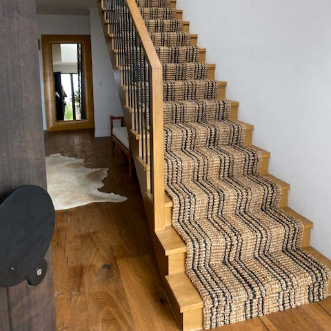 Staircase with a striped carpet runner in a home interior.