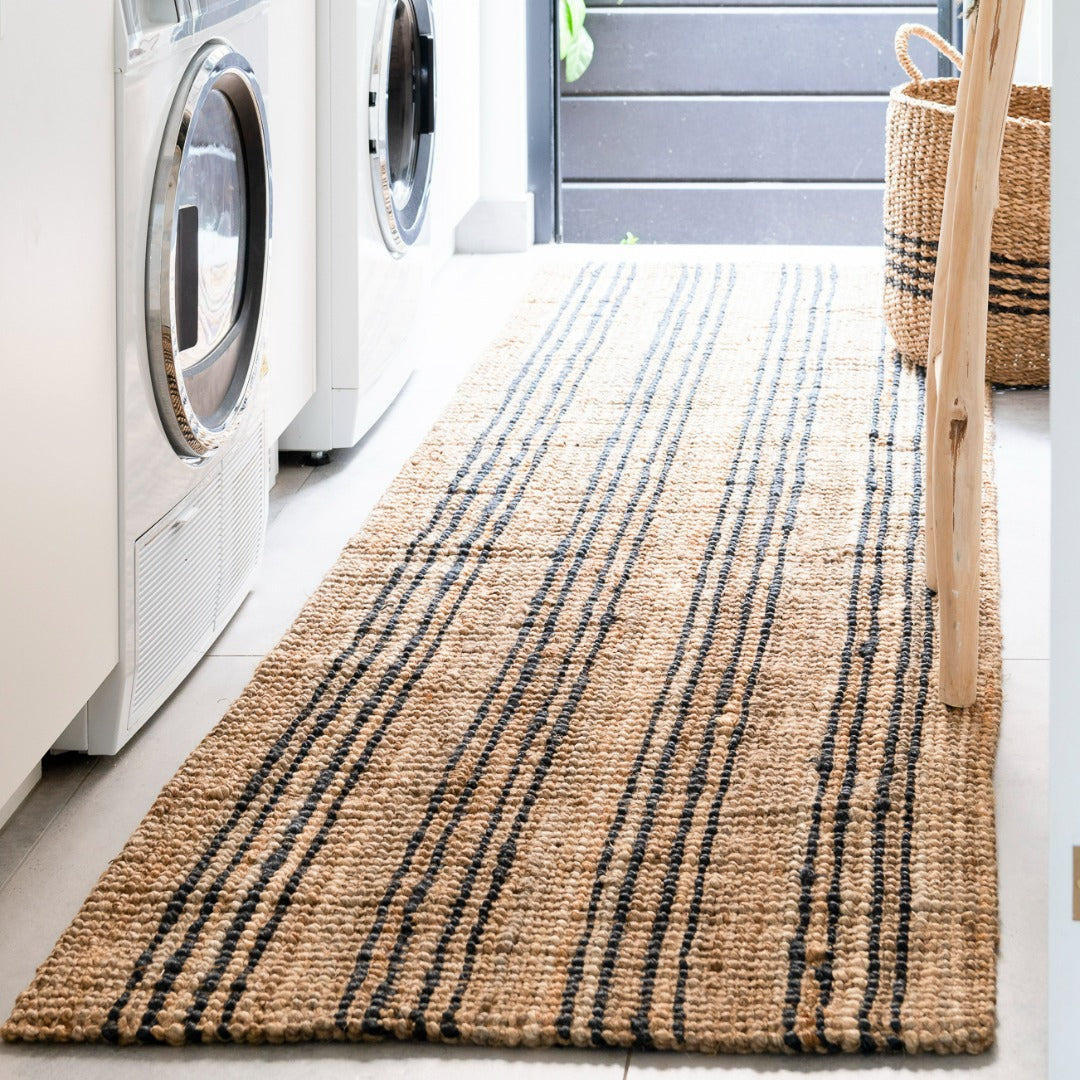 Laundry room with a striped jute rug, washing machines, and a basket.