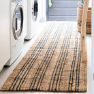 Laundry room with a striped jute rug, washing machines, and a basket.