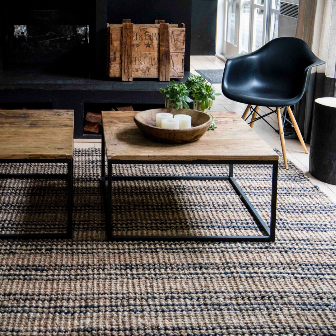 Living room with wooden coffee table, black chair, and textured rug