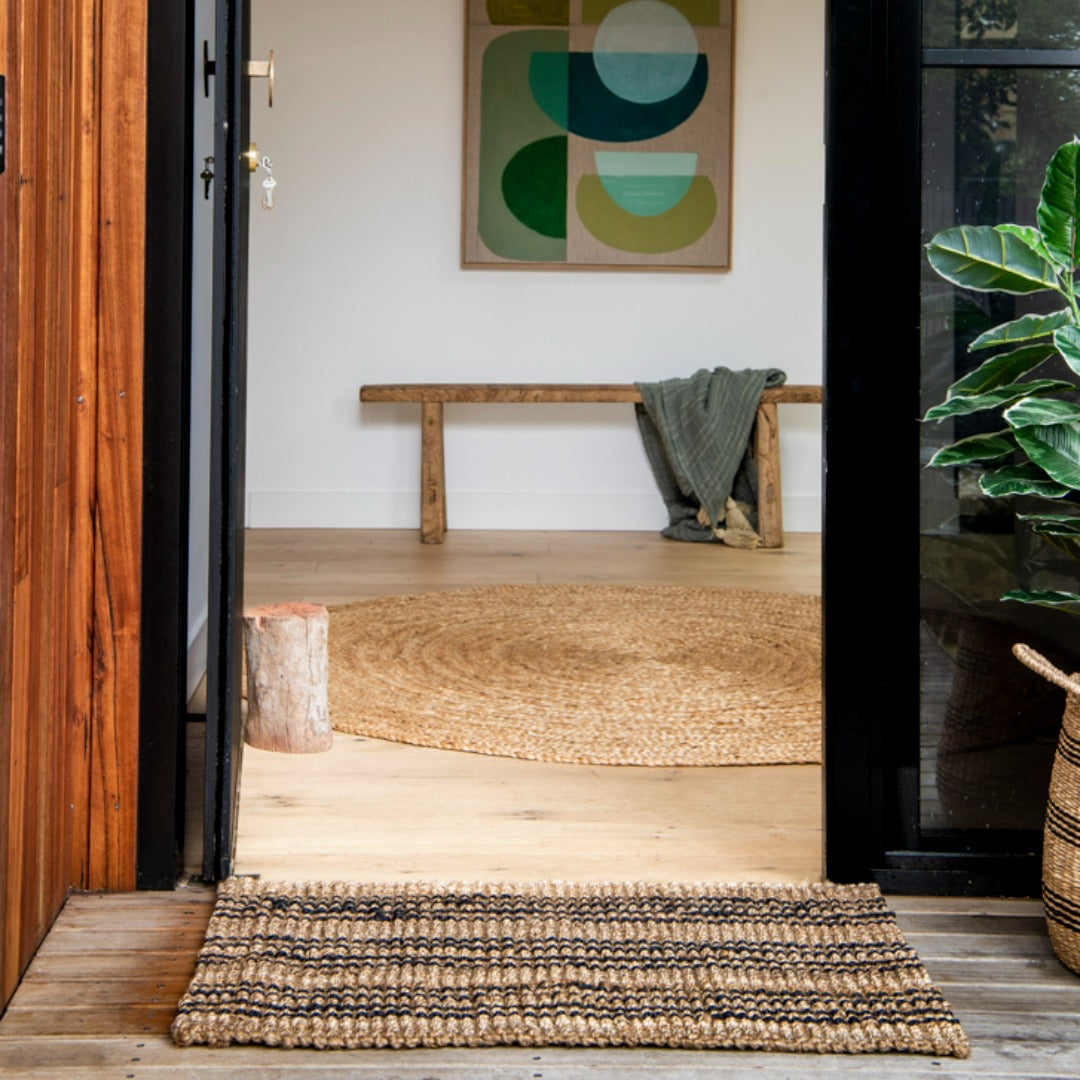 Entryway with woven mat, wooden bench, and abstract art on wall