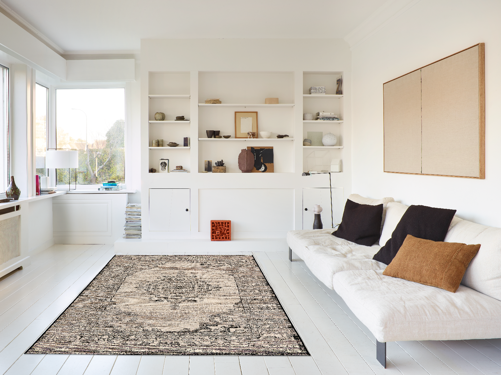 Modern living room with white walls, a rug, and a sofa with pillows.