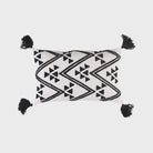Decorative pillow with black geometric pattern and tassels on a white background