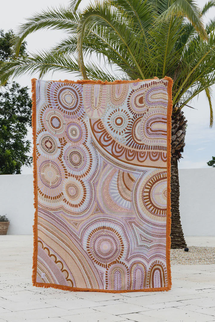Decorative throw blanket with circular patterns hanging against a palm tree