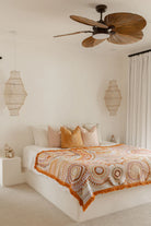 Bedroom with a ceiling fan, lamps, and a patterned bedspread.