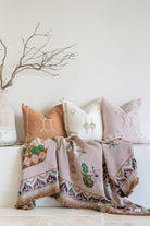 Decorative pillows and blanket with cactus design on a white surface