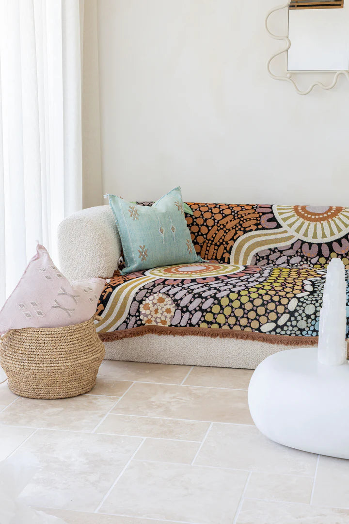 Decorative sofa with colorful patterned throw blanket and cushions in a living room setting.