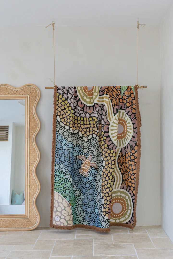Colorful abstract tapestry hanging on a wall next to a mirror.