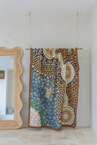 Colorful abstract tapestry hanging on a wall next to a mirror.
