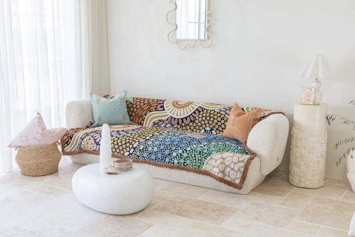 Decorative quilt on a sofa in a bright living room with a mirror and candles.