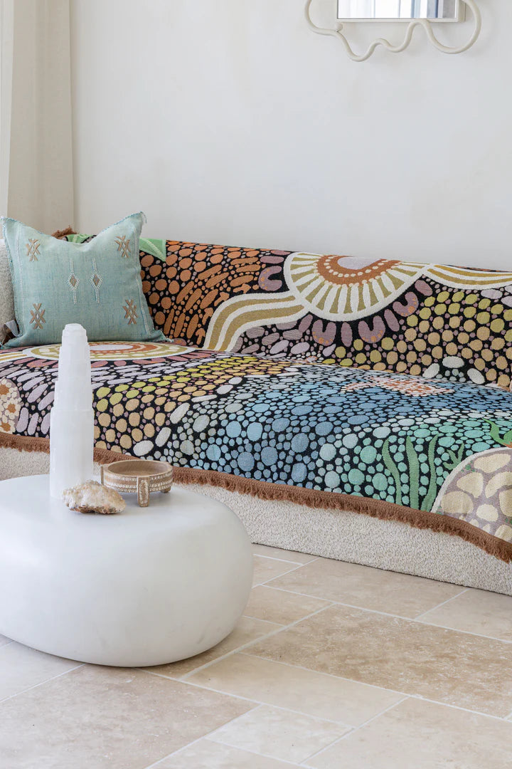 Colorful patterned sofa with a white ottoman and decorative items in a room.