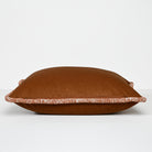A square brown throw pillow with a patterned border trim, photographed against a clean white studio background.