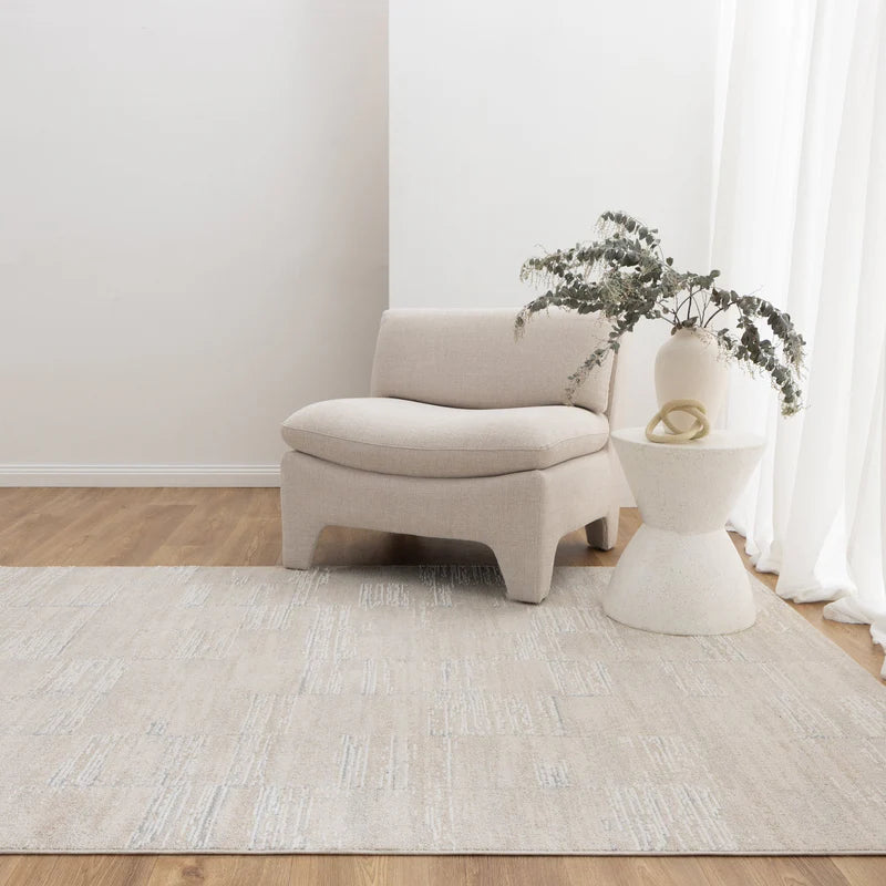 Beige armchair and side table with a plant in a minimalistic room.