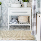 Bathroom with white vanity, towels, and a rug on a light gray floor.
