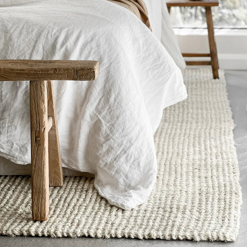 Bedroom with a wooden bench and textured rug