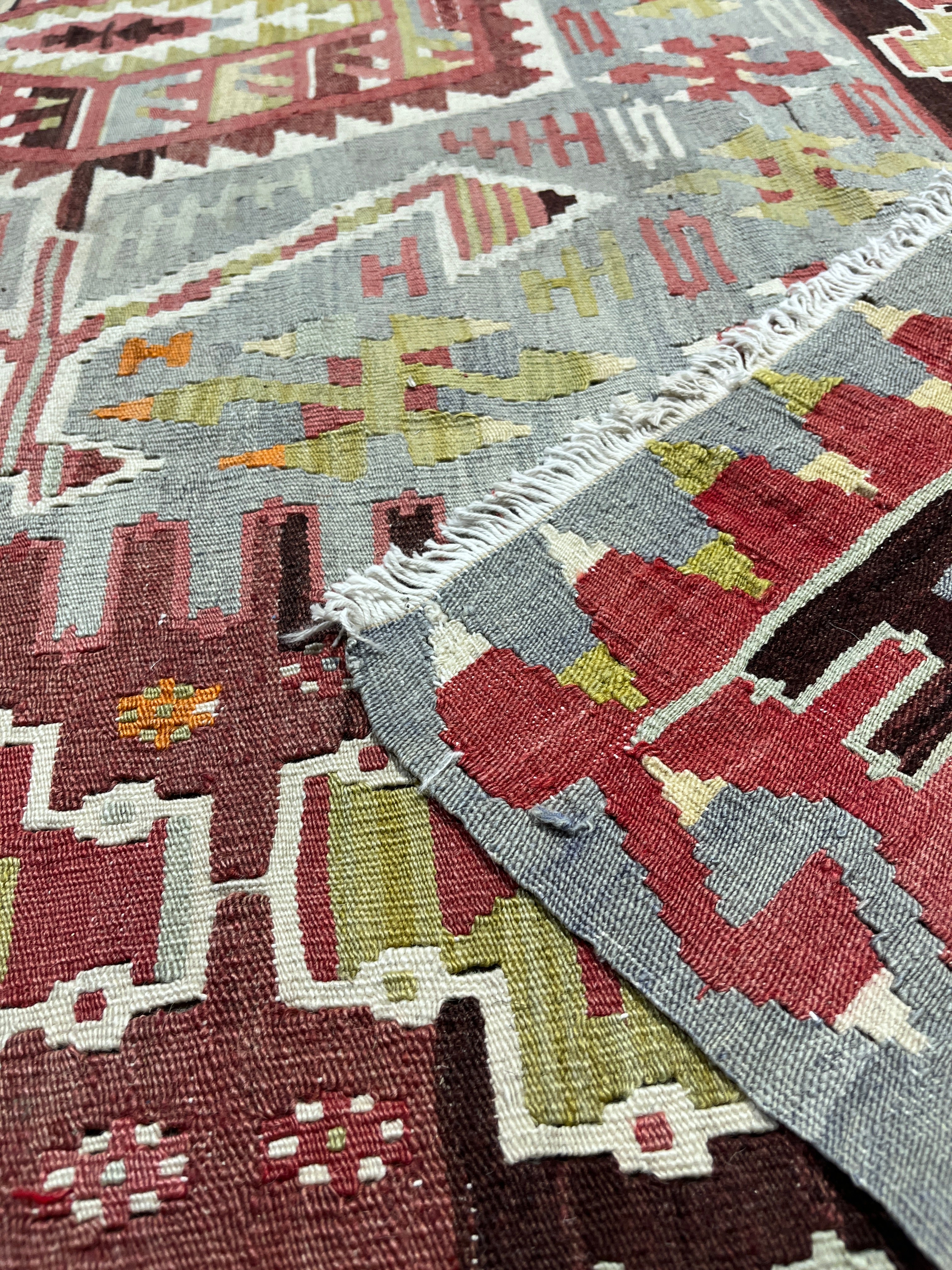 Close-up of patterned rugs with geometric designs in red, gray, and green.