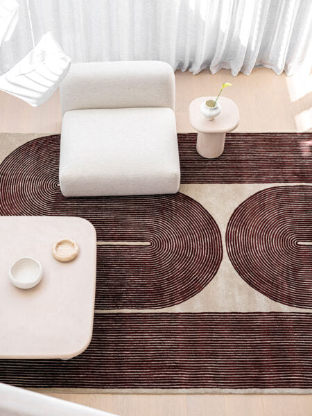 Modern living room with a patterned rug, white armchair, and side table.