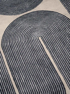 Close-up of a textured rug with circular patterns in black and beige.