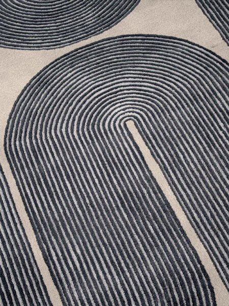 Close-up of a textured rug with circular patterns in black and beige.