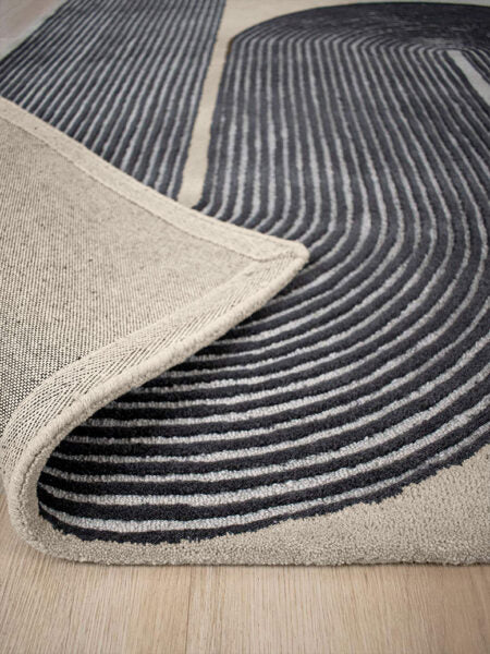 Close-up of a gray and black patterned rug on a wooden floor