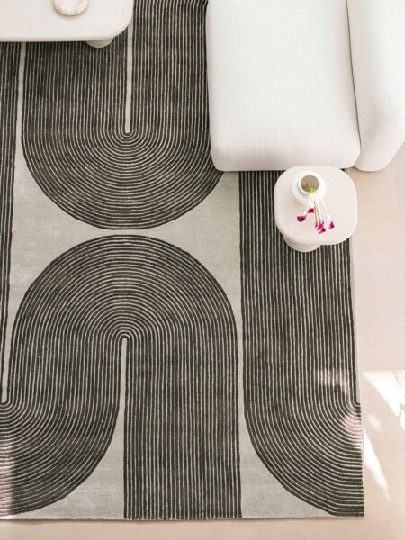 Gray area rug with black abstract patterns on a light-colored floor.