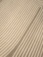 Close-up of a textured area rug with diagonal stripes in beige and taupe gray.