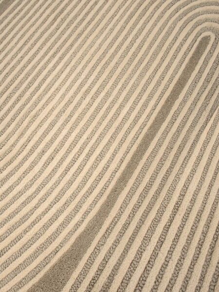 Close-up of a textured area rug with diagonal stripes in beige and taupe gray.