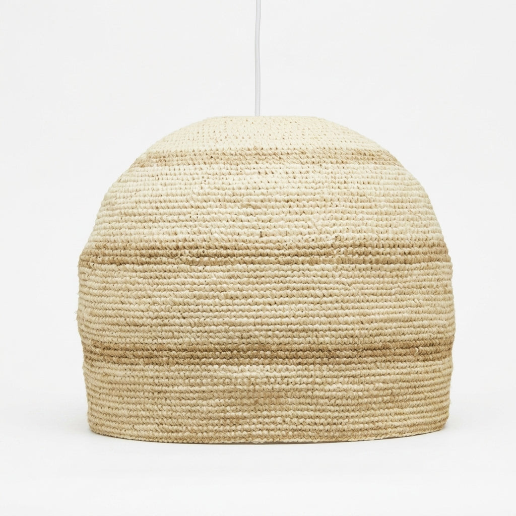 A woven pendant light shade made from natural jute or seagrass, featuring a textured horizontal striped pattern in shades of beige and tan, suspended from a thin white cord against a plain white background.