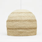A woven pendant light shade made from natural jute or seagrass, featuring a textured horizontal striped pattern in shades of beige and tan, suspended from a thin white cord against a plain white background.