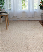 Beige woven rug in a room with white curtains and plants.