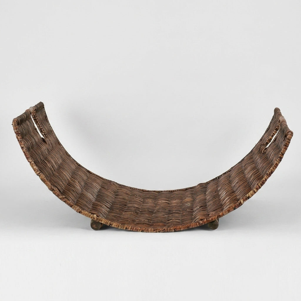 A curved, hand-woven basket or tray with integrated handles and small feet, shown against a plain light gray studio background.