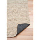 Beige textured rug with dark border on a wooden floor